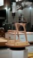 Six-axis robotic arm CNC-milling the curved back and seat support of a wooden chair frame on a rotating worktable
