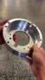 Freshly machined aluminum flange with central bore, milled slots, and tapped holes produced on a CNC turning and milling center